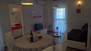 A modern living room with a dining table, a sofa, a TV, and a window with curtains. - Villa Duje Old town (Trogir)