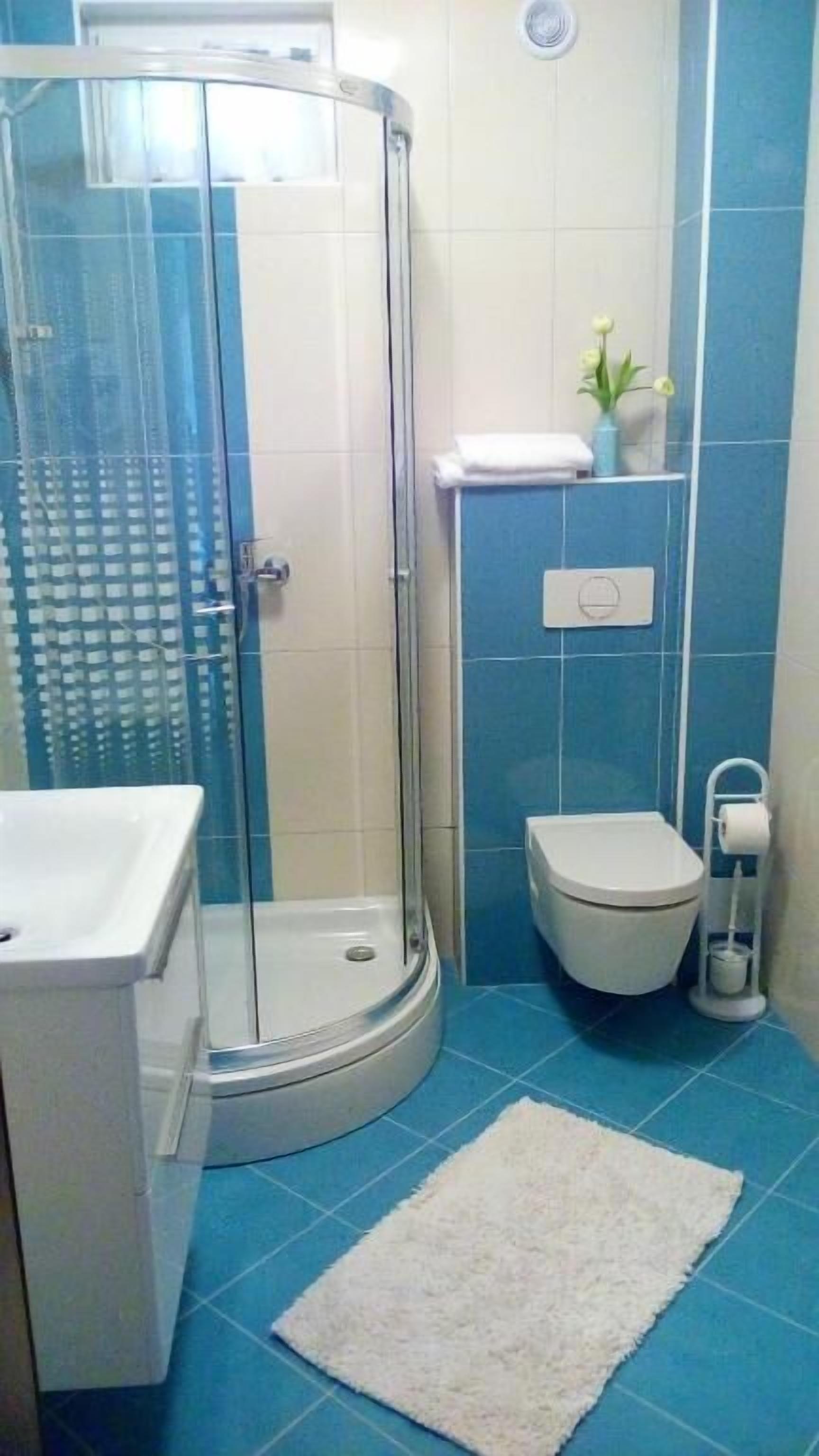 A bathroom with a glass-enclosed shower, a toilet, and a sink.