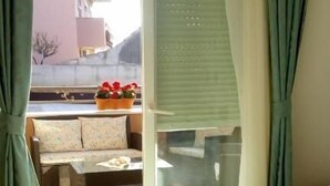 Ein Schlafzimmer mit einem Bett, einem Fenster und Blick auf einen Außenbereich mit Sitzgelegenheiten.
