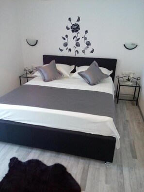 A bedroom with a large bed, two bedside tables, and a wall-mounted light fixture. - Villa Duje Old town (Trogir)