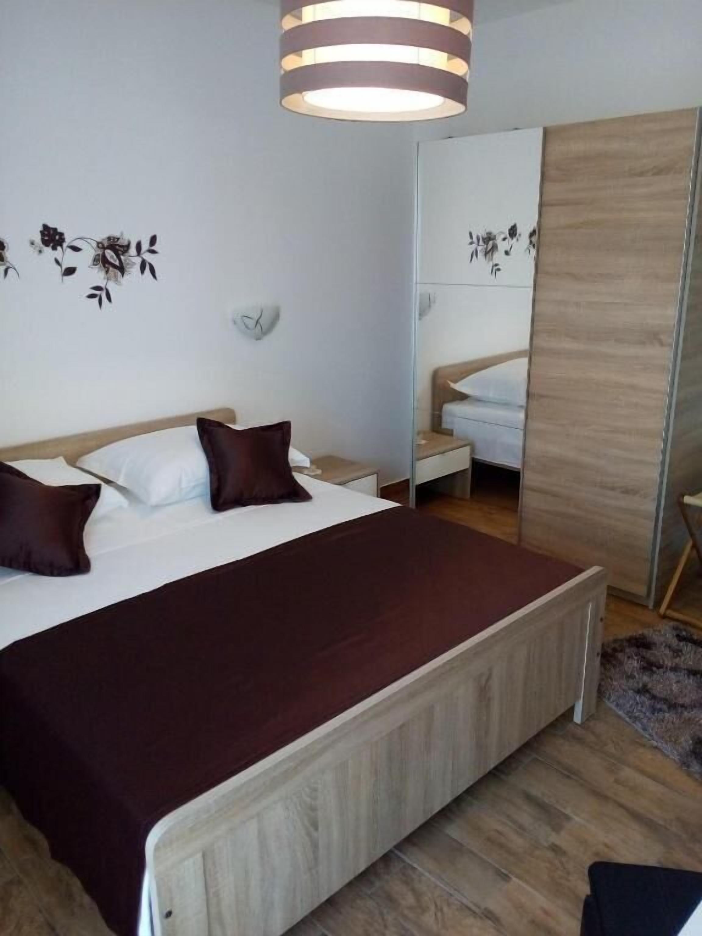 A bedroom with a bed, bedside tables, a mirror, and a wardrobe.