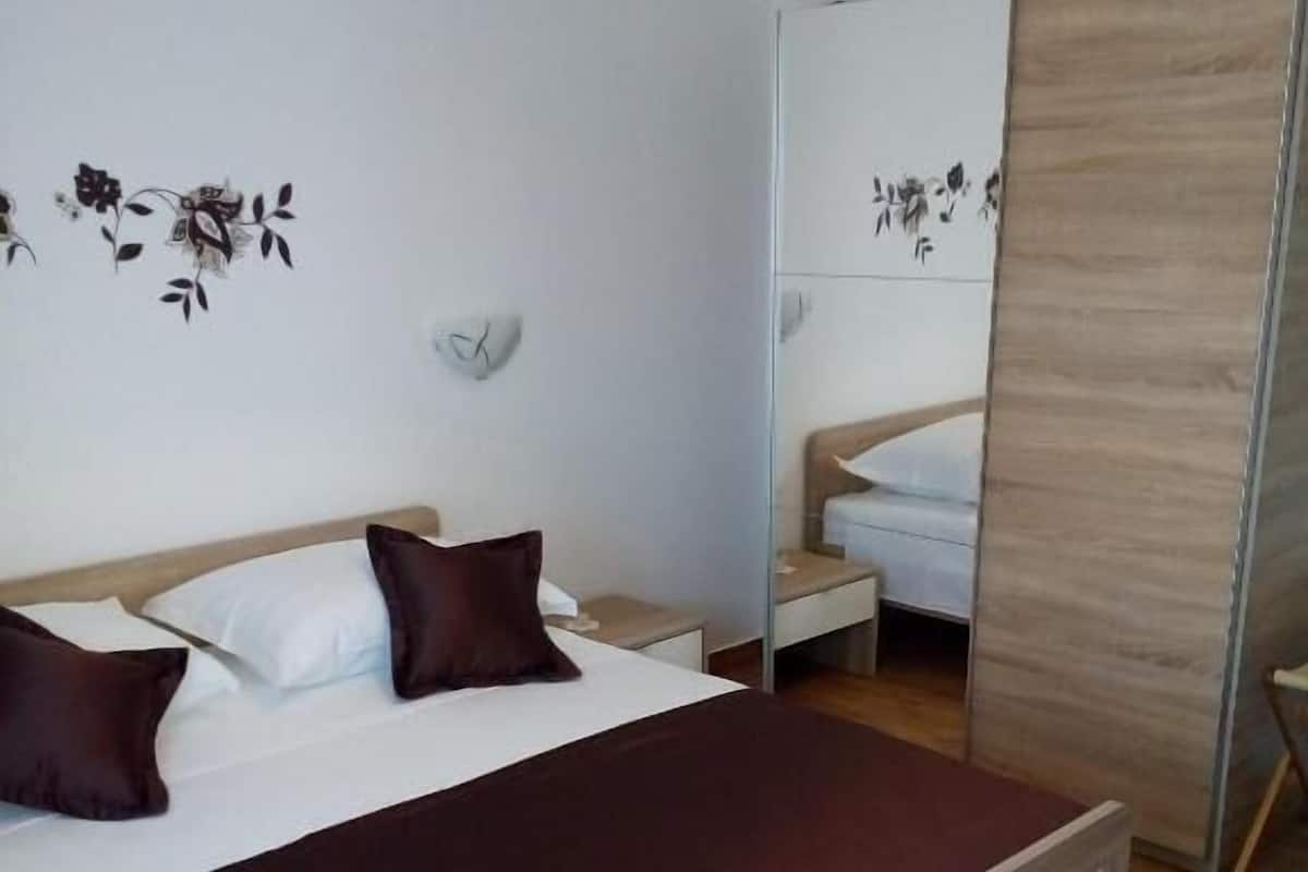 Un dormitorio con cama, mesitas de noche, un espejo y un armario.
