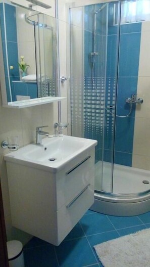 A bathroom with a glass-enclosed shower, a white sink, and a mirror above it. - Villa Duje Old town (Trogir)