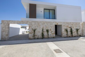 Un bâtiment moderne à deux étages, doté d’une façade en pierre, de grandes fenêtres et surplombant un ciel dégagé.
