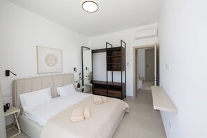 Une chambre à coucher comprenant un lit, une table de chevet, une œuvre d’art accrochée au mur et une armoire.