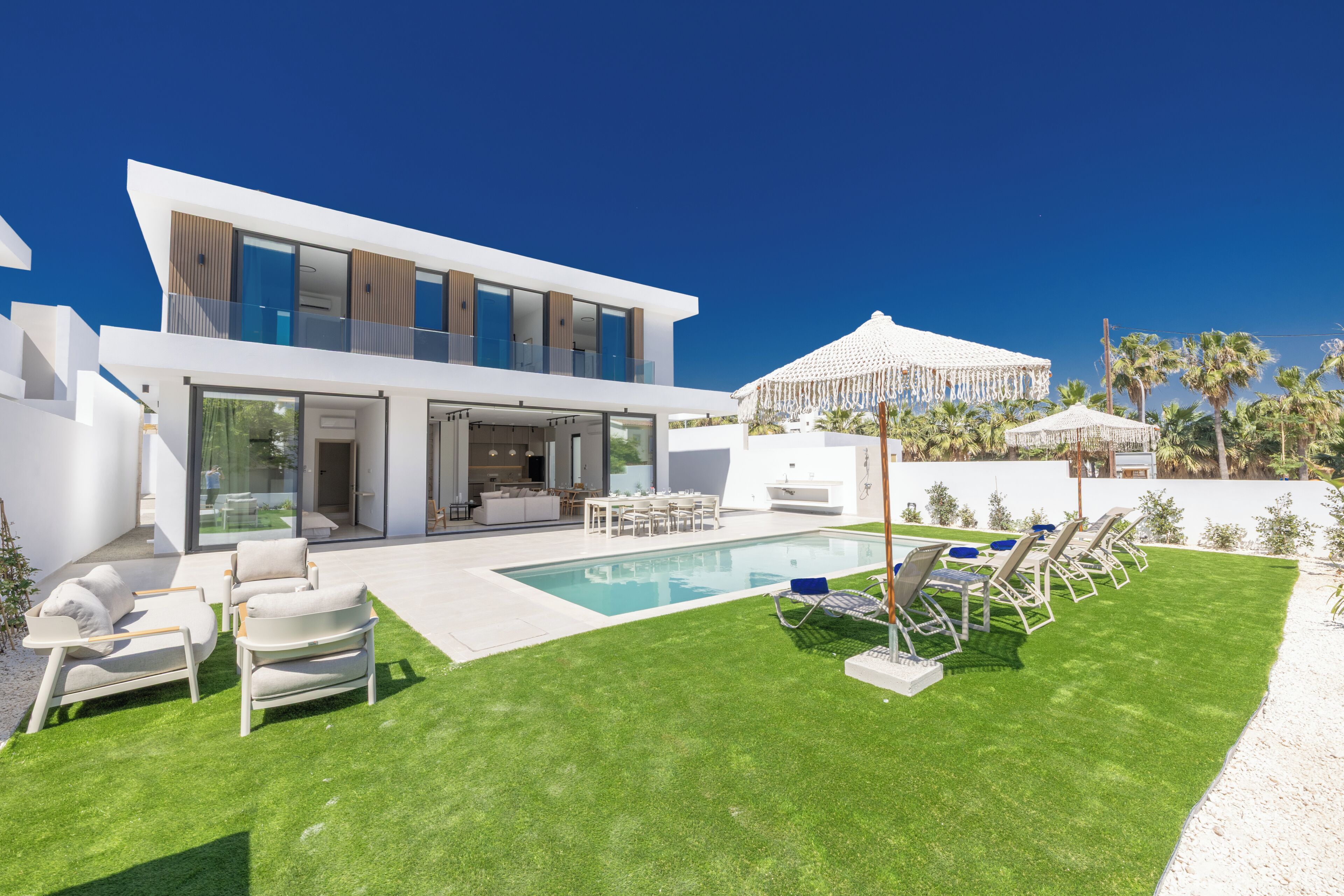 Une maison moderne dotée d’une piscine, d’un espace extérieur aménagé et d’une zone couverte.