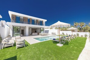 A modern house with a swimming pool, outdoor seating, and a covered area. - Brand New 4 Bedroom Villa with private pool, 100 meters from the beach (Protaras)