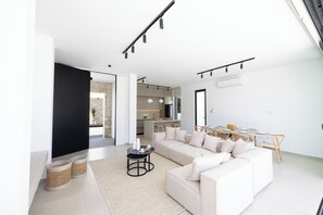 A modern living room with a sofa, coffee table, and dining area.