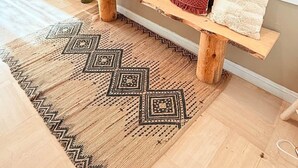 Eine hölzerne Bank mit Kissen, ein gemustertes Teppich und wandmontierte Spiegel.