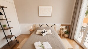 Ein ordentlich eingerichtetes Schlafzimmer mit einem Bett, Nachttischen, einem Wandregal und einem Fenster mit Vorhängen.
