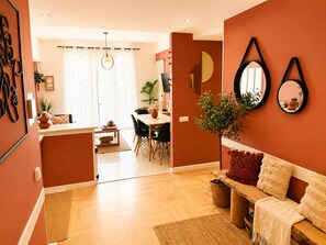 Un salon moderne avec un plancher en bois, un canapé, un coin repas comprenant une table et des chaises, et un coin cuisine avec un comptoir et des placards.