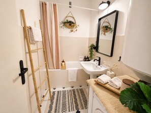 Une salle de bain équipée d’une douche, d’un lavabo, d’un miroir et d’un porte-serviettes.