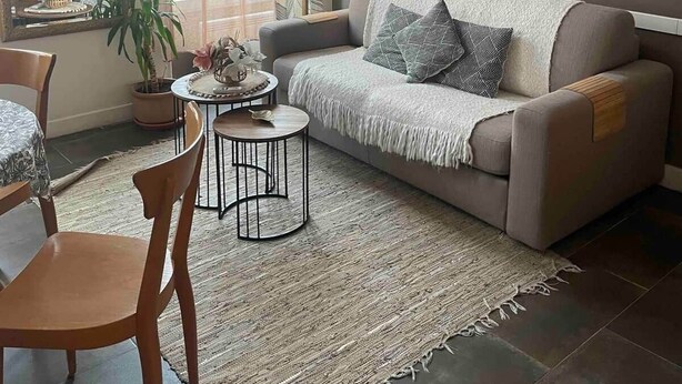 Ein Wohnzimmer mit einer Couch, einem Couchtisch, einem Sessel, einer Hängeleuchte und einem Fenster mit Vorhängen.