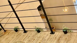 A wooden floor with woven mats, a metal railing, and potted plants. - Nice Old Town 3BR Duplex - AC, Easy Check-in, Cathedral Area (Nice)