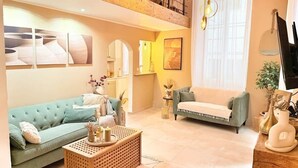 A spacious living room with a high ceiling, a green sofa, a white sofa, and a wooden coffee table. - Nice Old Town 3BR Duplex - AC, Easy Check-in, Cathedral Area (Nice)
