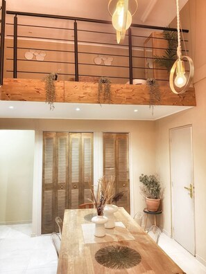 Un comedor con una mesa de madera, sillas y una lámpara colgante.