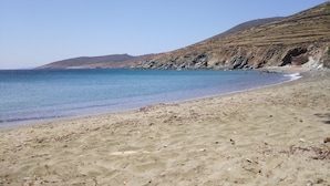 En strand med klart vatten, en sandstrand och klippiga branter.