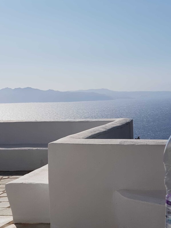 A seaside view with a clear sky, a calm sea, and distant mountains.