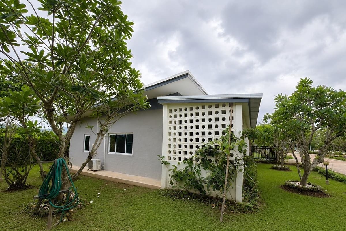 A modern house with a flat roof, a white fence, and a well-maintained lawn.