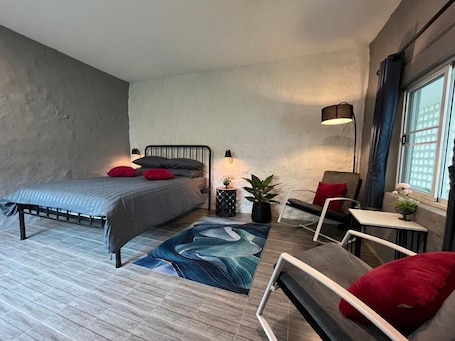 Une chambre à coucher moderne avec un lit, des tables de chevet, une chaise, une petite table et une fenêtre.. Banana Village Resort