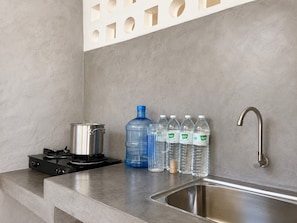 A kitchen with a gas stove, a sink, and water bottles. - Banana Village Resort (Mae Taeng)