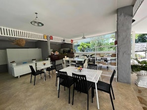 A dining area with a white table and black chairs, a white counter with a plant, and a view of the outside. - Banana Village Resort (Mae Taeng)