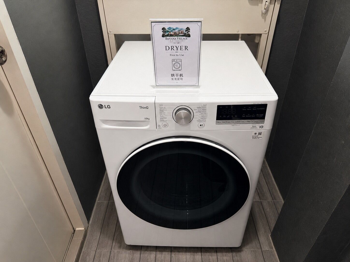 A white LG ThinQ dryer in a laundry room with a sign above it.