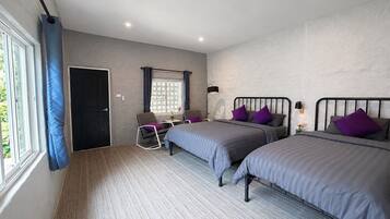 A bedroom with two beds, a desk, a chair, and a window with curtains.