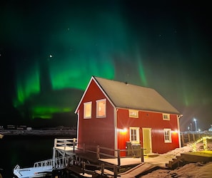 A red building with a dock, windows, and a door. - New and exclusive cabins with fantastic sea views, right by the sea. (Nordland)