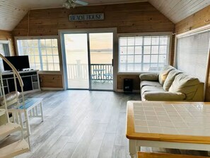 Ein Holzinterieur mit einer Couch, einem Tisch, einem Fernseher und einem Schild mit der Aufschrift 'Beach House'.