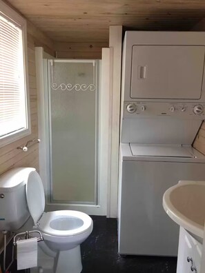 Ein kleines Badezimmer mit Toilette, Dusche und Waschmaschine.