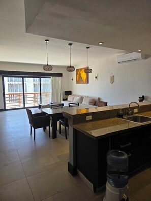 A modern kitchen with a dining area, a water dispenser, and a large window with a view. - Aldea Thai, Ocean front penthouse w/ private rooftop patio & pool w/ ocean view. (Playa del Carmen)
