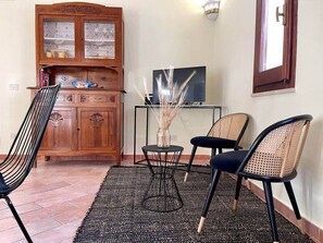 Ein Zimmer mit einem Holzkasten, einem Fernseher und drei Stühlen.