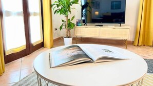 A room with a round table, a potted plant, a flat-screen TV, and a cabinet.
