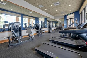 Un gimnasio con equipo cardiovascular, máquinas de pesas y espejos.
