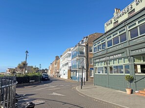 Una calle con edificios, incluyendo un restaurante llamado 'The Charles Dickens' y un pub llamado 'Dickens'.