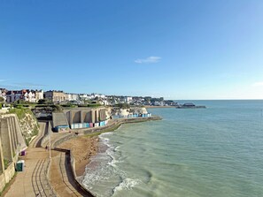 A coastal town with a promenade, buildings, and a sea view.