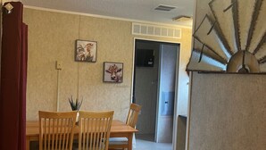 A dining area with a wooden table and chairs, a red curtain, and two wall-mounted pictures.