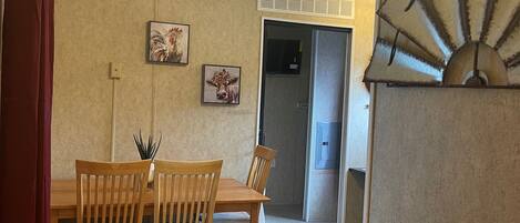 A dining area with a wooden table and chairs, a red curtain, and two wall-mounted pictures.