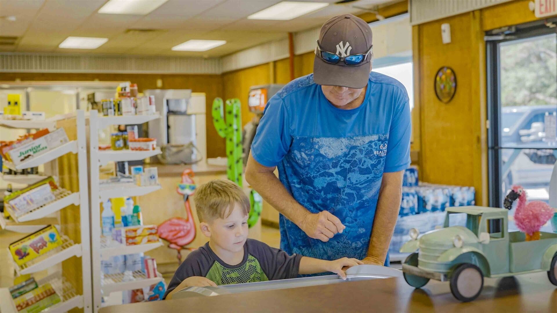 A man and a child in a store with shelves stocked with products.