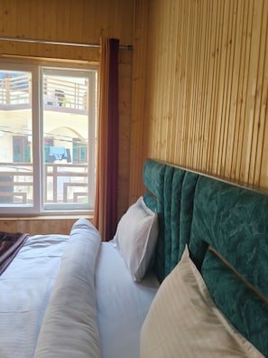 A room with a bed, a window, and wooden walls.