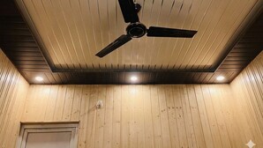 A ceiling fan in a room with wooden paneling and recessed lighting. - Yamuna pag pinewood hotel  (Rajgarhi)