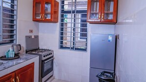 Cocina con estufa a gas, horno, refrigerador de acero inoxidable y gabinetes de madera.