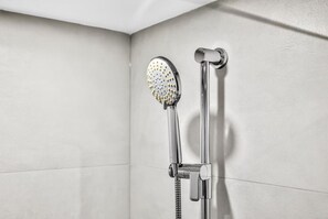 Una ducha con cabezal de ducha de mano y llave de control en la pared.