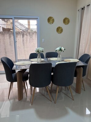 Zona pranzo con tavolo in vetro, sedie scure e decorazioni a parete.
