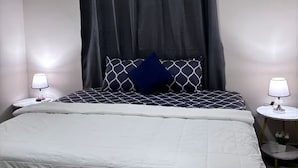 Una camera da letto con un letto, una finestra, un condizionatore d'aria e due comodini con lampade.