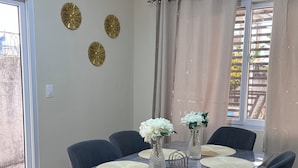 Zona pranzo con tavolo in marmo, sedie nere e decorazioni a parete.
