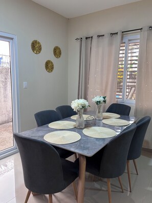 Un comedor con una mesa de mármol, sillas negras y elementos decorativos en la pared.