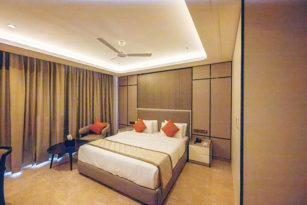 Een moderne hotelkamer met een groot bed, een bureau, een stoel, een nachtkastje en een plafondventilator.