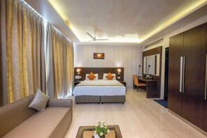 A hotel room with a bed, a sofa, a desk, and a mirror.